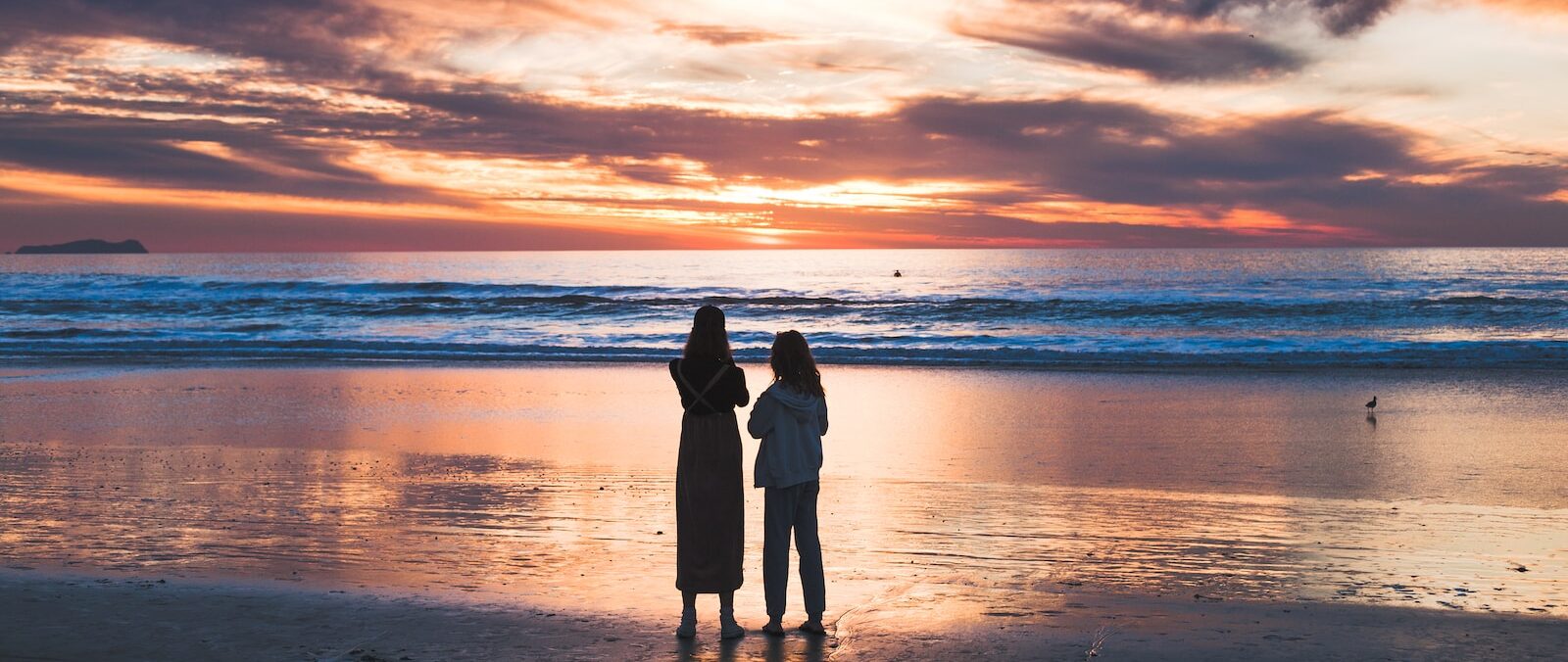 woman and girl standing on seashore